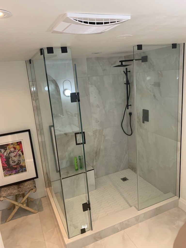 Bathroom with glass walk-in shower, marble surfaces and black fixtures