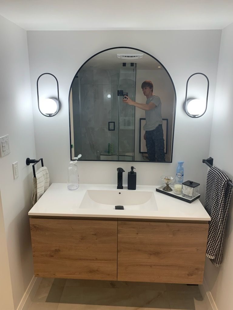 Bathroom with floating wood vanity and an arched mirror